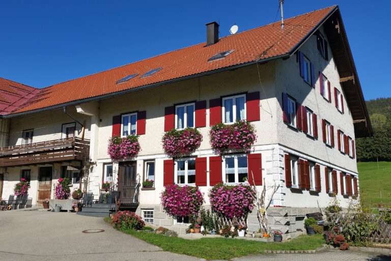 Weißes Bauernhaus mit roten Fensterläden